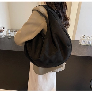 Close-up of a large black suede tote bag showing soft texture and spacious slouchy design