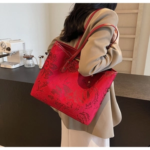 Close-up of red jacquard fabric tote bag with vintage floral patterns and leather handles