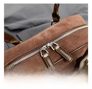 Detail of a brown matte leather bowling bag with silver double zippers and fine stitching