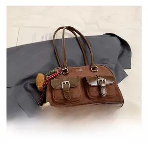 Detailed shot of brown suede shoulder bag with dual flip pockets and silver buckles