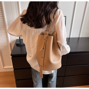 Detail view of beige lychee leather bucket bag with silver hardware and adjustable strap