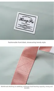 Detailed view of reinforced pink webbing straps and woven logo on green oxford travel bag
