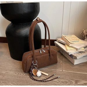 Detailed view of brown suede underarm bag with zipper and baseball charms decoration