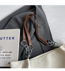 Détail du sac fourre-tout crème avec bandoulière marron et grosse chaîne argentée