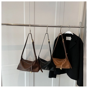 Détail de sacs fourre-tout en cuir souple marron, noir et caramel suspendus à un support
