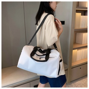 White waterproof sports travel bag with black straps worn by a model in a cozy setting