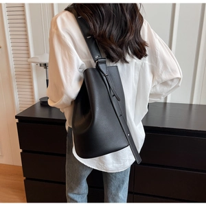 Detailed view of black lychee grain leather bucket bag with wide adjustable shoulder strap