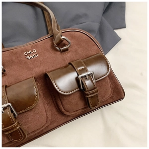 Detail of vintage brown shoulder bag showing suede texture and silver buckle pockets