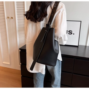 Detail of black lychee leather bucket bag with adjustable wide strap on model back