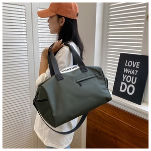 Detail view of army green gym bag with waterproof fabric and white brand label on handles