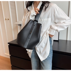 Close-up of black litchi pattern leather bucket bag with wide adjustable shoulder strap