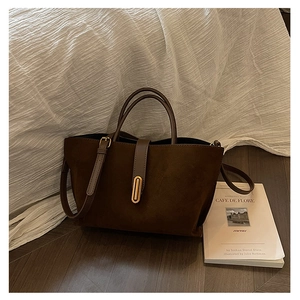 Detail of dark brown faux suede tote bag featuring adjustable strap and golden hardware