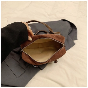 Macro detail of the spacious beige fabric interior lining of the brown suede handbag