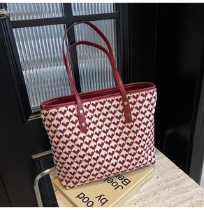 Detail of red pixel heart tote bag featuring durable handles and gold rivet accents