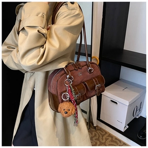 Detail of vintage suede bowling bag with dual front buckles and a teddy charm