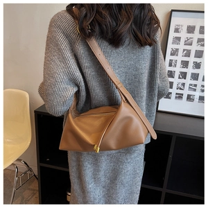 Sac cabas marron en cuir avec plis et fermeture éclair dorée porté par le modèle