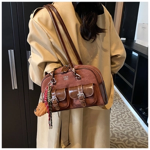 Detail showing vintage brown suede bowling bag with dual front pockets and bear charm