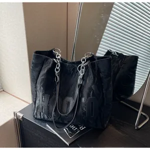 Détail du sac cabas noir texturé avec écusson HOOTO et poignée en chaîne argentée