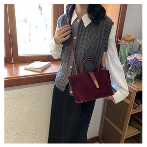 Detail of burgundy suede tote bag with gold metal buckle shown in a lifestyle setting