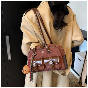 Detailed back view of a brown suede bowling bag with side bear charm on a trench coat