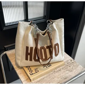 Détail du cabas plissé blanc avec logo HOOTD en cuir marron et bandoulière chaîne métal
