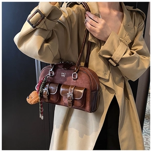 Detail of vintage brown suede hobo bag with buckled pockets and plush bear charm accessory