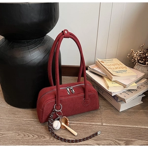 Detail of burgundy suede shoulder bag with baseball charms and silver zipper close-up