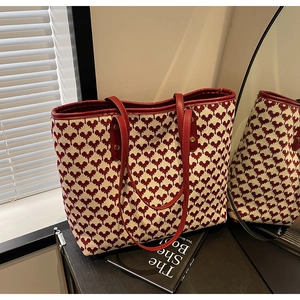 Detail of red heart-pattern tote bag with premium leather handles on wooden table