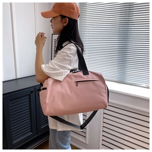 Pink waterproof travel bag showing adjustable logo straps and side zipper pocket details
