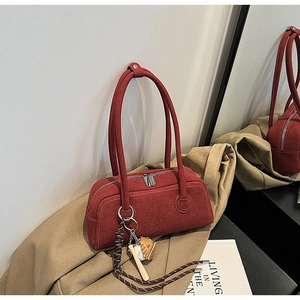 Detail of reddish brown suede Boston bag with embossed logo and baseball charm