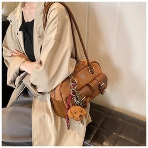 Detail of a brown Boston bag with teddy charm and suede texture on beige coat