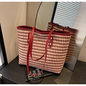 Detail of red houndstooth tote bag with deep red leather handles and gold rivet accents
