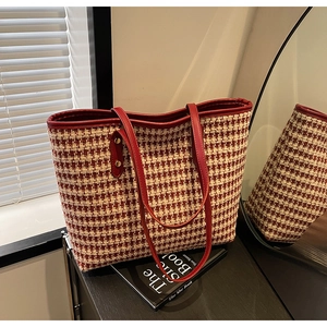 Close-up of red and white houndstooth tote bag with leather handles on vintage books