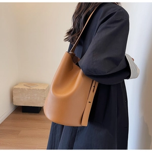 Detail view of the caramel brown lychee leather texture and rivet on this bucket bag