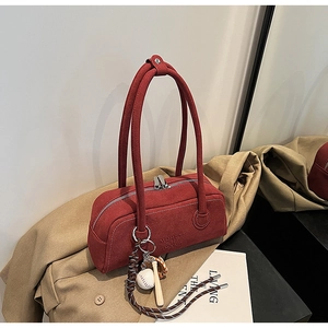 Close-up of red suede underarm bag with silver zippers and baseball charm detail