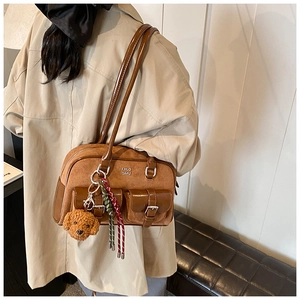 Detail view of brown suede retro shoulder bag with plush dog charm and woven strap accents