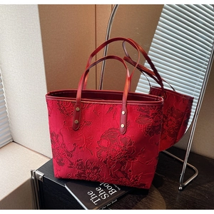 Detailed view of red floral embroidery on luxury tote bag with leather handles