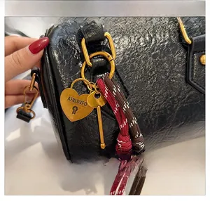 Detail of glossy black Boston bag with gold heart lock and vintage key charm
