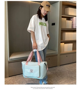Detail of mint green Oxford cloth travel bag with pink handles and front zipper pocket