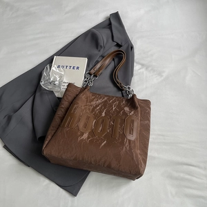 Détail du sac cabas marron foncé montrant la texture plissée et la bandoulière chaîne