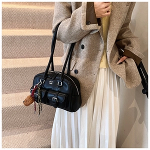 Detail of black matte leather shoulder bag with silver buckles and autumn outfit