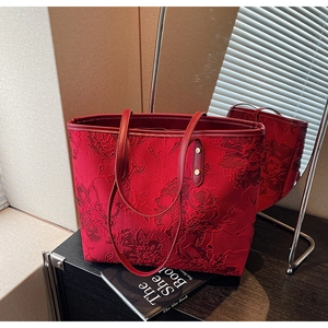 Detail shot of the red tote bag featuring intricate floral embroidery and leather handles