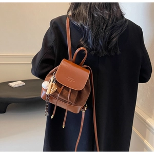 Detail of brown PU leather mini backpack with suede panels and baseball keychain charm