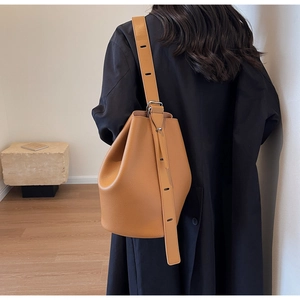 Caramel brown pebbled leather bucket bag with silver metal buckle on adjustable strap