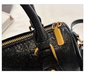 Close-up of litchi grain black leather texture and vintage gold metal zipper hardware