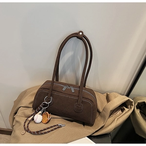 Detail view of dark brown suede shoulder bag featuring a unique baseball glove charm