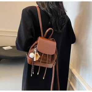 Detail view of mini dark coffee backpack with suede texture and sports themed charms