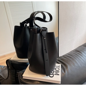 Detailed view of black lychee grain leather bucket bag with decorative side straps