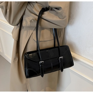 Dettaglio della borsa baguette in vernice nera lucida con fibbie argento e doppi manici