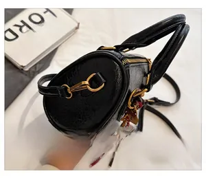 Detail view of black Boston bag with textured leather, gold zipper and tassel charm
